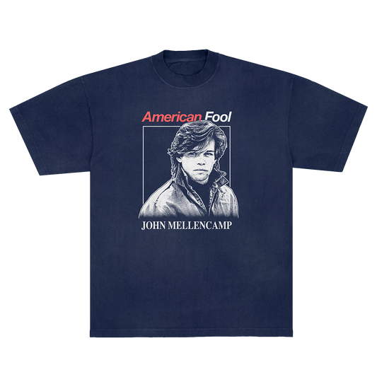 A navy blue short-sleeve t-shirt with a graphic print on the front. The graphic features the text 'American Fool' in red and white, a black-and-white portrait of John Mellencamp, and 'JOHN MELLENCAMP' printed below in white